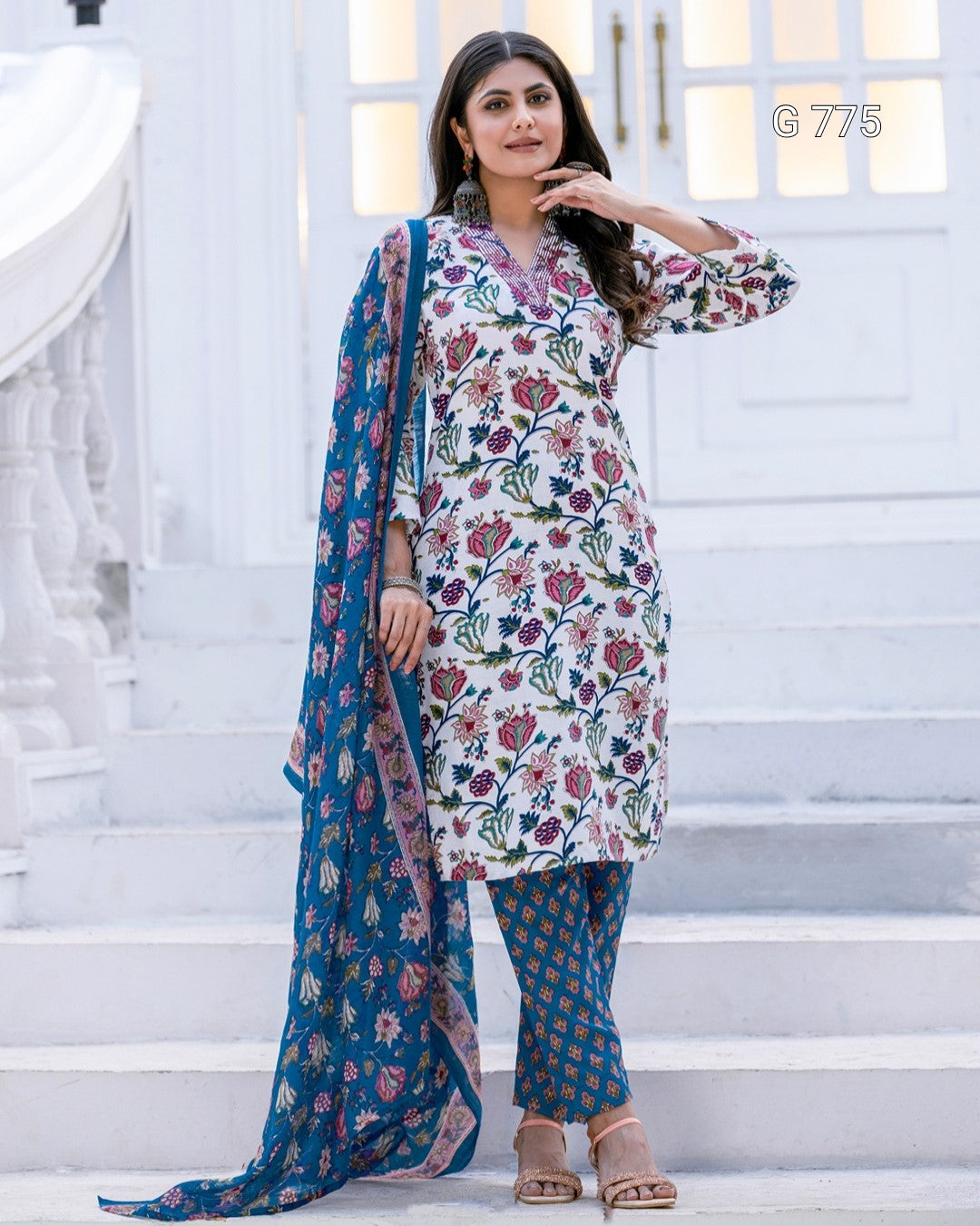 Woman wearing a floral kurta with a blue dupatta on a white staircase