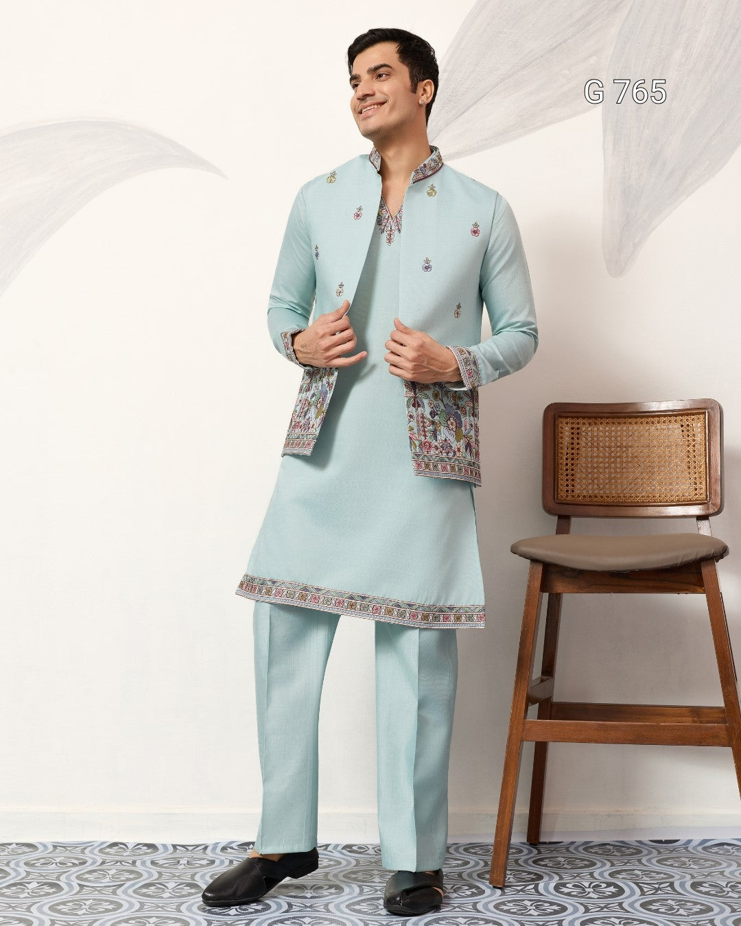 Man wearing a light blue traditional outfit with a chair in the background