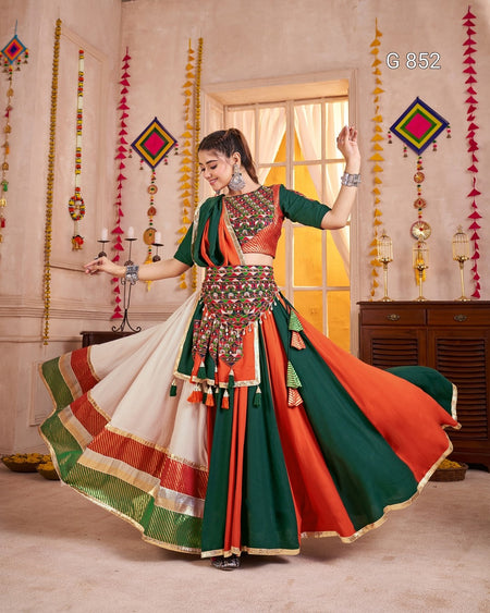 Woman in a traditional outfit with vibrant colors dancing in a decorated room.