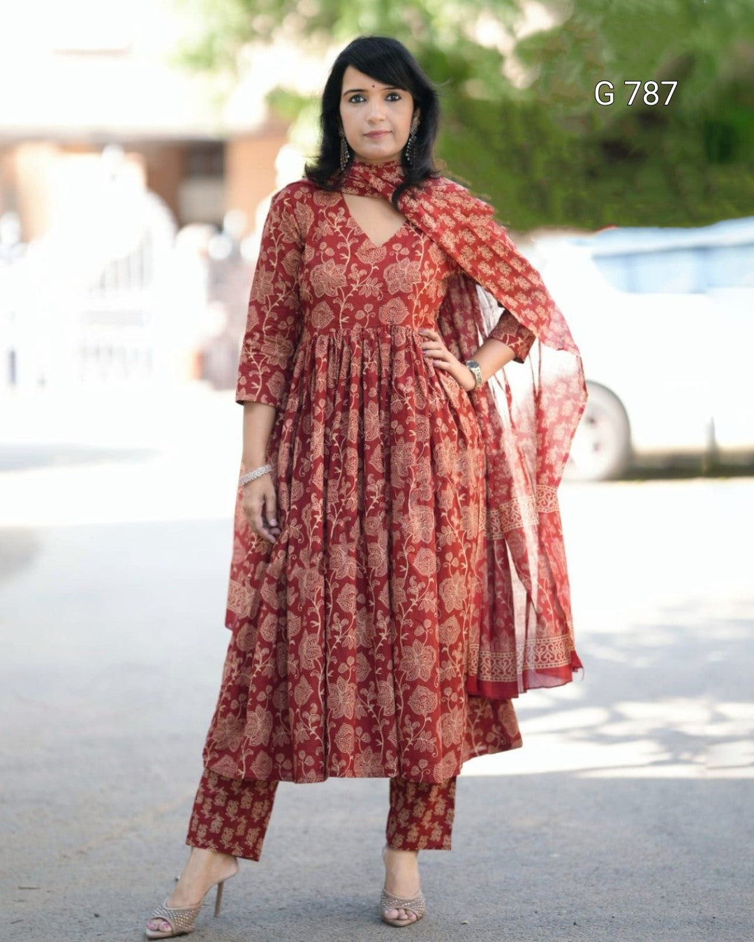 Woman wearing a red patterned dress with a scarf in an outdoor setting