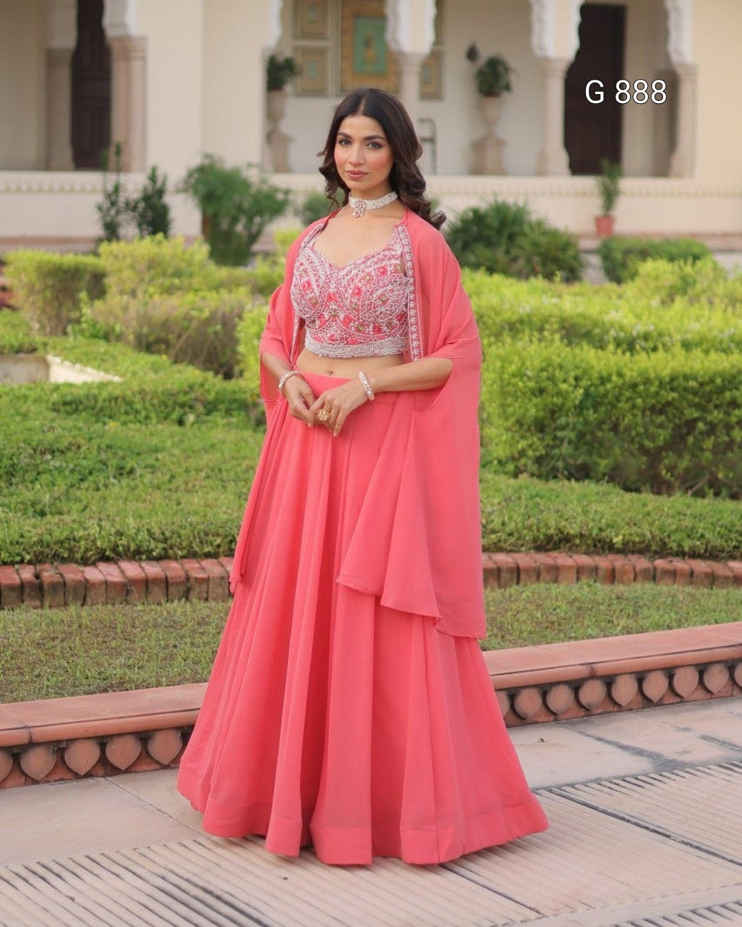 Woman in a pink traditional outfit standing in a garden setting