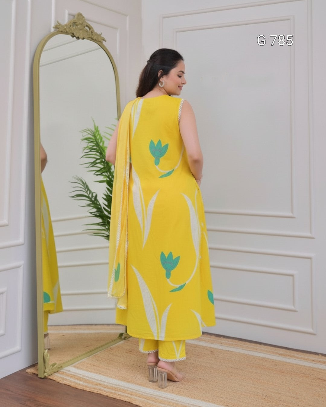 Woman in a yellow outfit with floral patterns standing in front of a mirror.