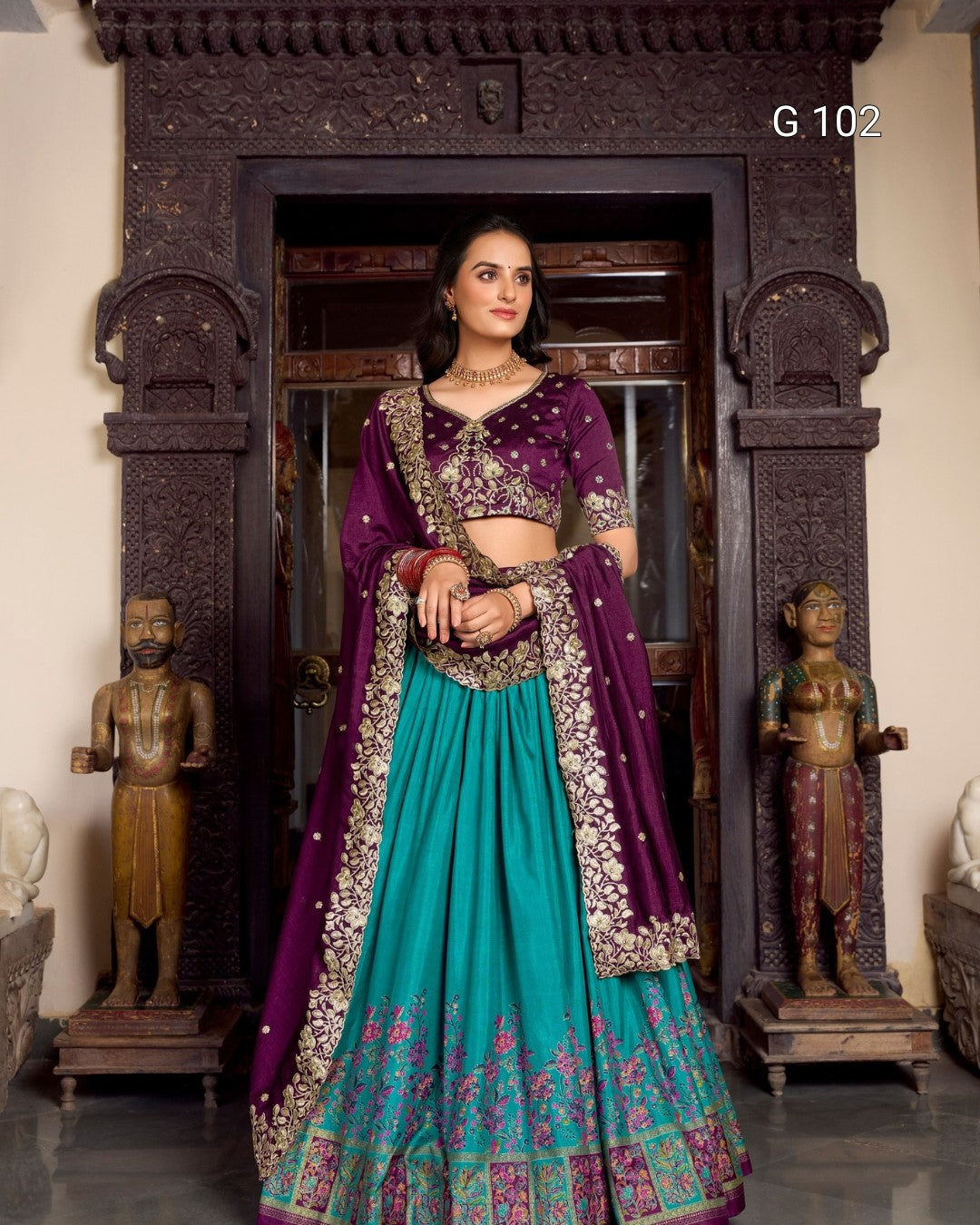 Woman in a traditional purple and teal outfit standing in an ornate doorway.