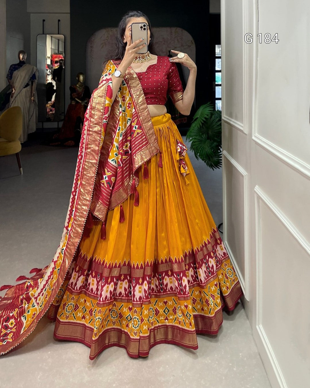 Person wearing a traditional yellow and red lehenga with a matching dupatta, standing in a room.