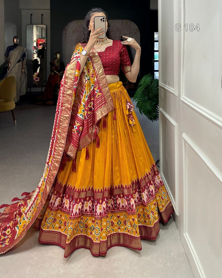Person wearing a traditional yellow and red lehenga with a matching dupatta, standing in a room.