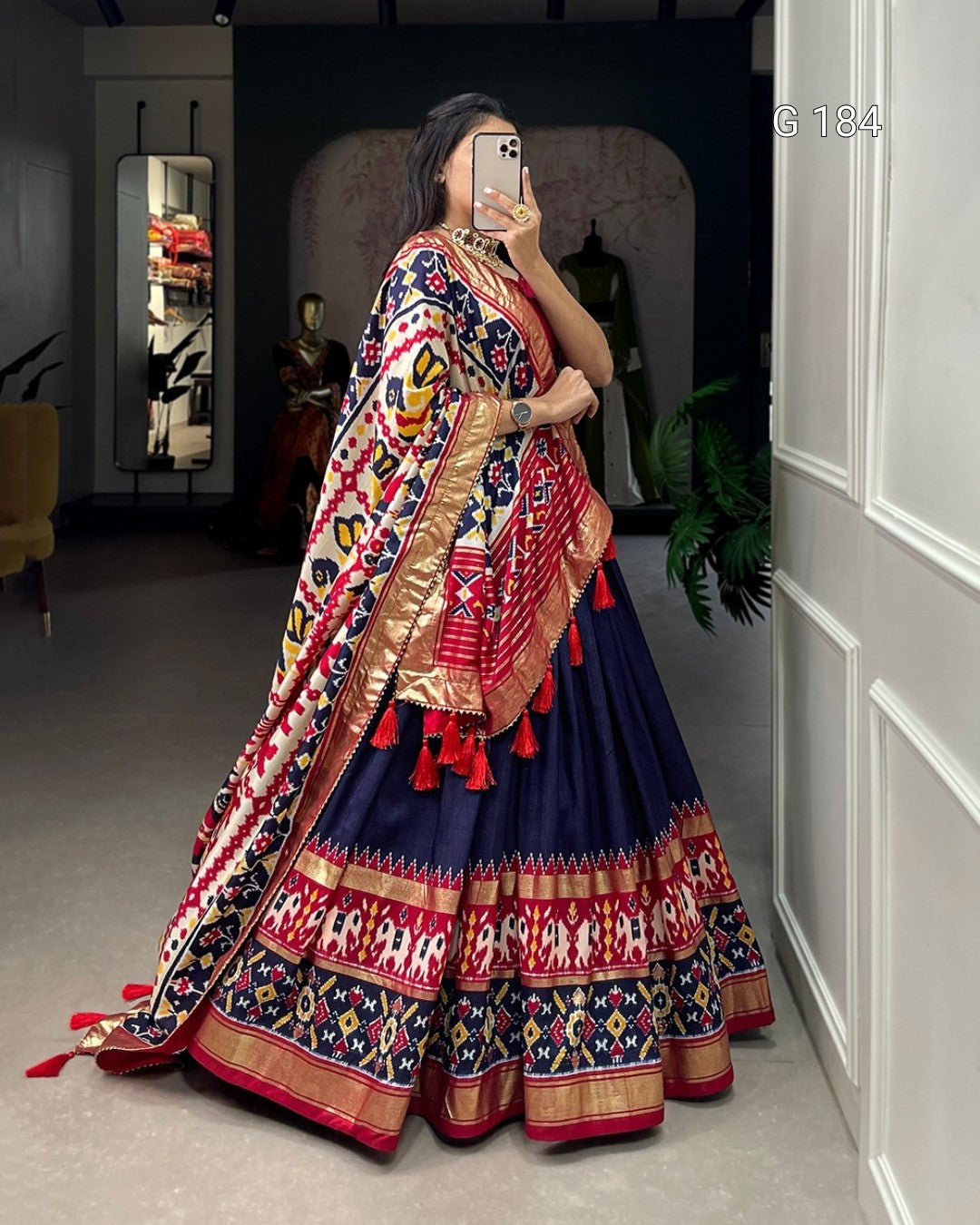 Woman in a colorful traditional outfit taking a mirror selfie.