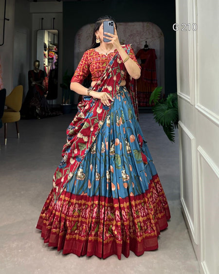 Woman wearing a colorful saree taking a mirror selfie in a room.