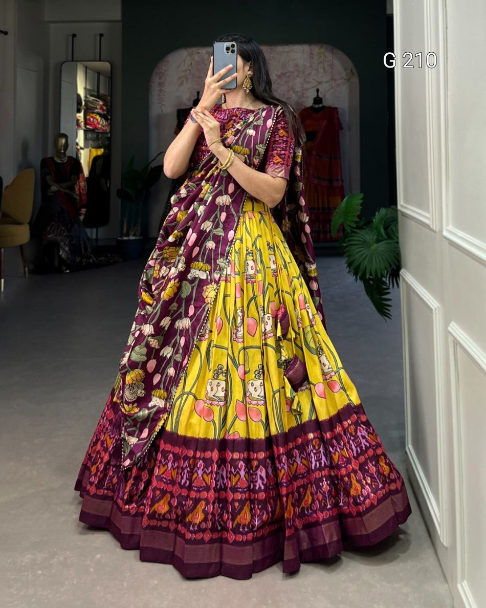 Woman wearing a colorful traditional outfit with a yellow and purple pattern, standing in a room.