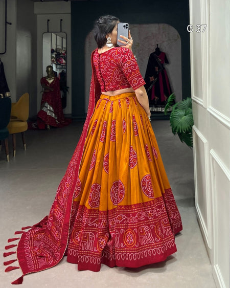 Woman taking a mirror selfie wearing a red and orange traditional outfit with intricate patterns.