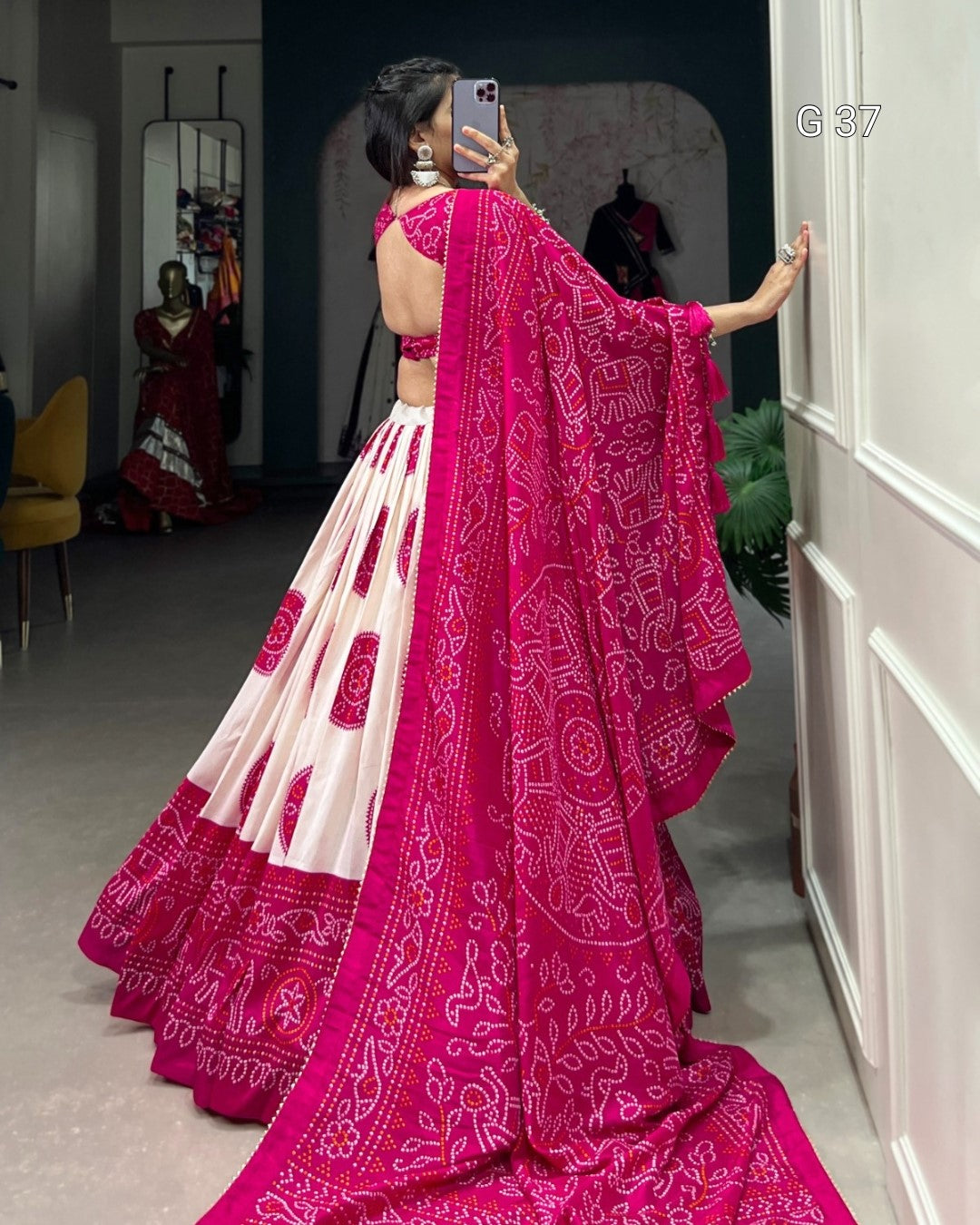 Woman wearing a pink and white saree with a pattern, standing in a room.