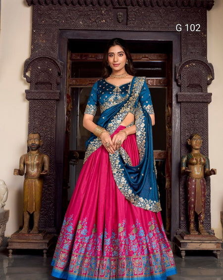 Woman in a blue and pink traditional outfit standing in front of decorative wooden panels.