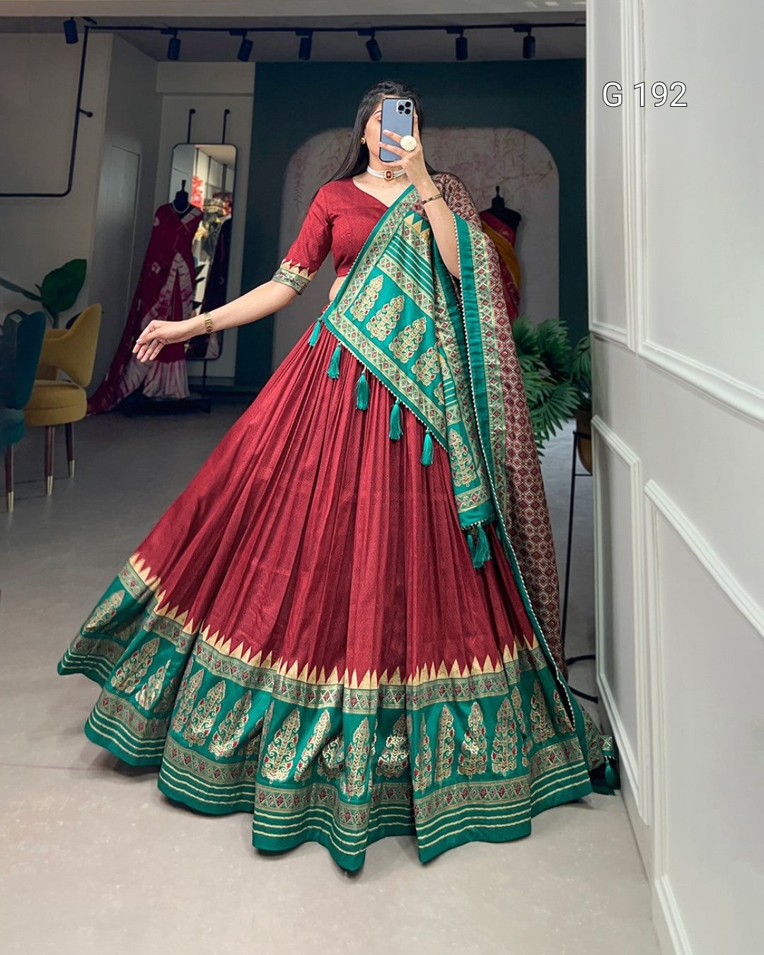 Red and green traditional outfit with matching dupatta in a room setting