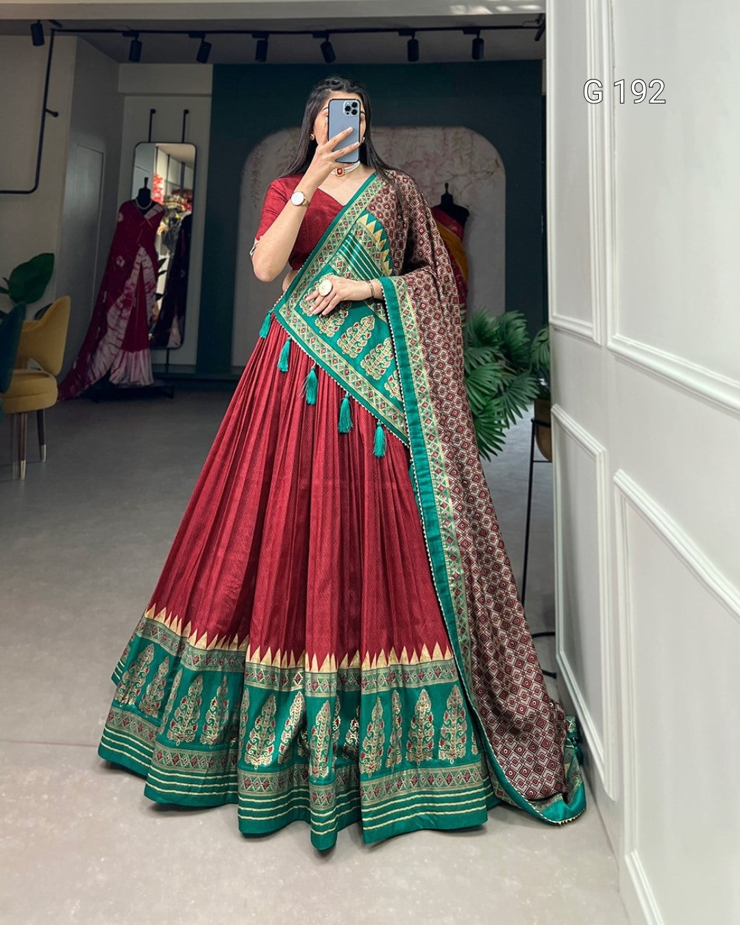 Red and green traditional outfit with a patterned dupatta in a room.
