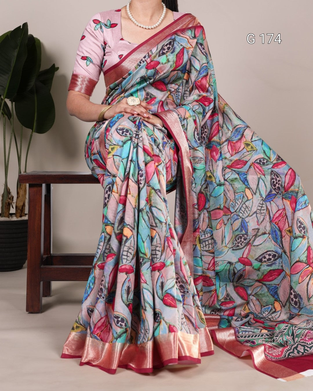 Colorful saree with intricate patterns draped over a person, with a neutral background.