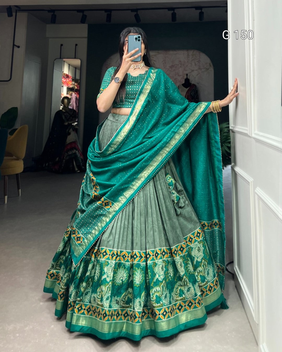 Person wearing a traditional green and gold saree with a matching blouse, standing in a room.