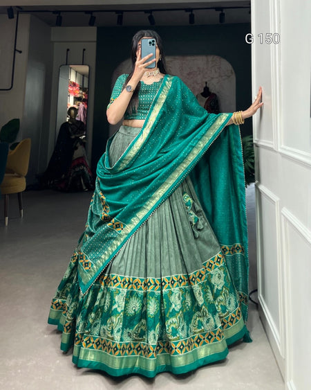 Person wearing a traditional green and gold saree with a matching blouse, standing in a room.