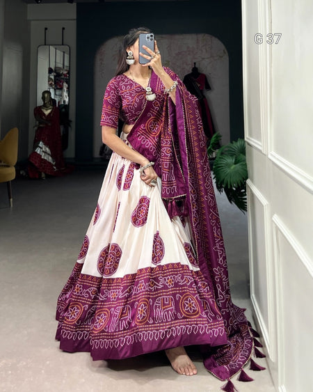 Woman wearing a traditional purple and white saree with elephant patterns, standing in a room.