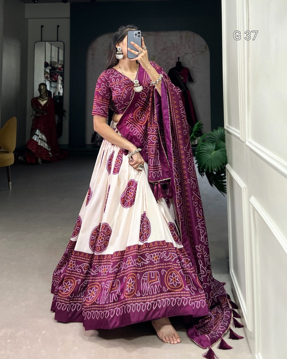 Woman wearing a traditional purple and white saree with elephant patterns, standing in a room.