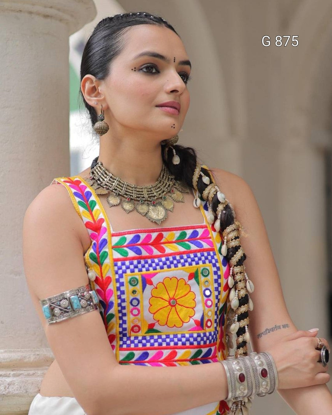 Woman wearing a colorful traditional outfit with intricate jewelry in an outdoor setting