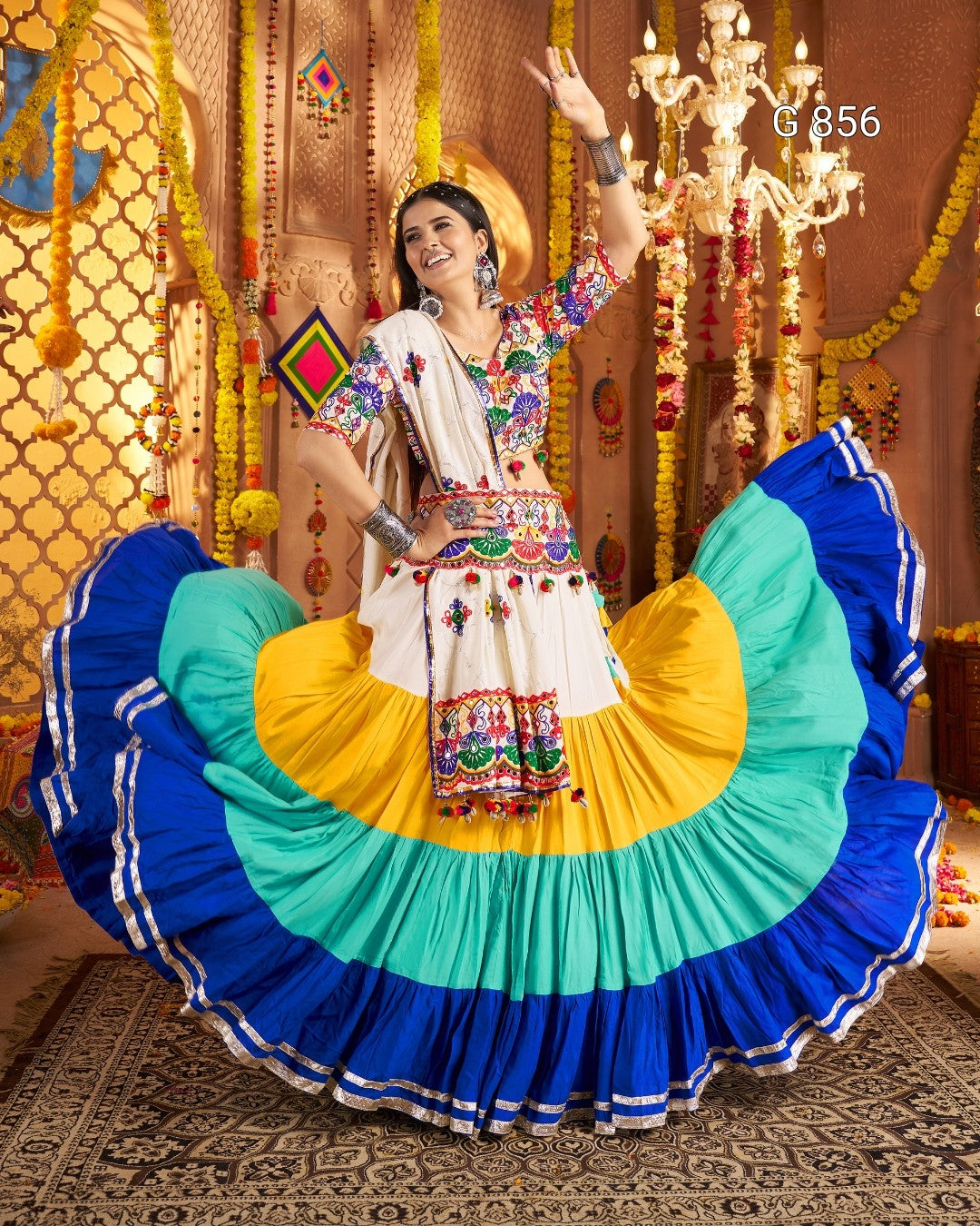 Woman in traditional colorful outfit with a large, multicolored skirt in a decorated indoor setting.