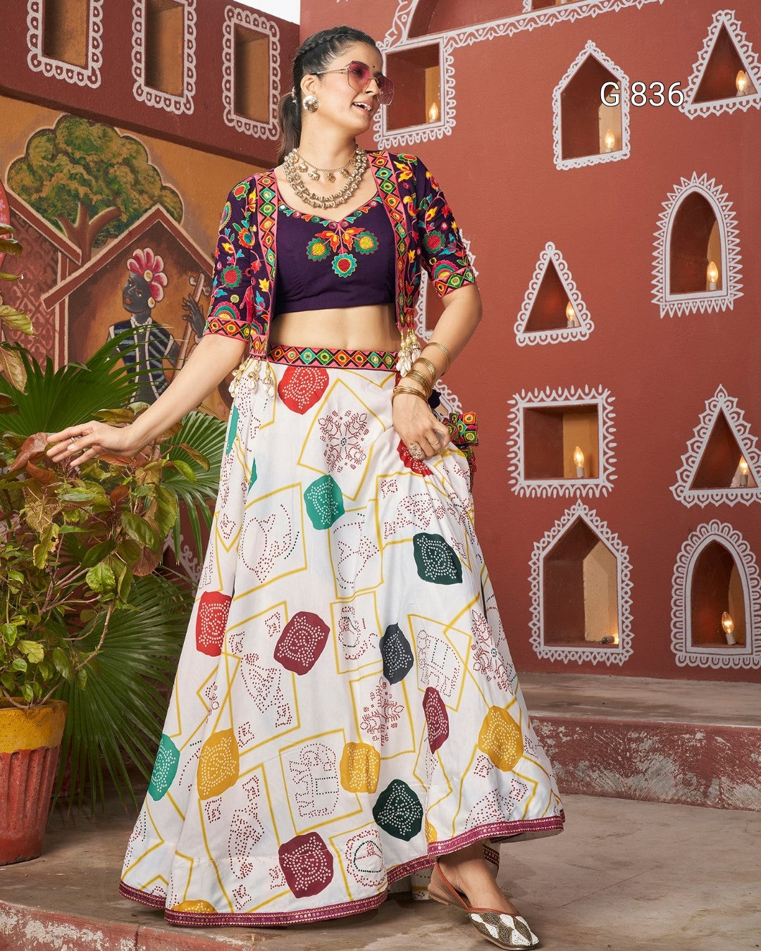 Woman in traditional outfit with colorful patterns against a decorative wall.