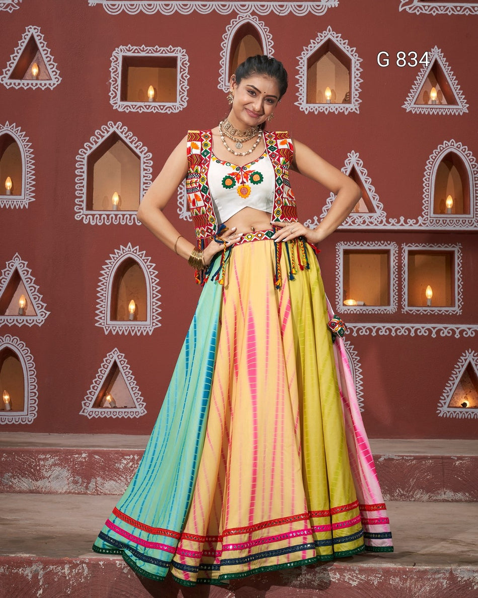 Woman in a colorful traditional outfit standing against a decorative wall.