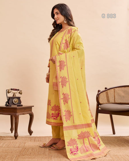 Woman wearing a yellow traditional outfit with pink patterns in a room setting.