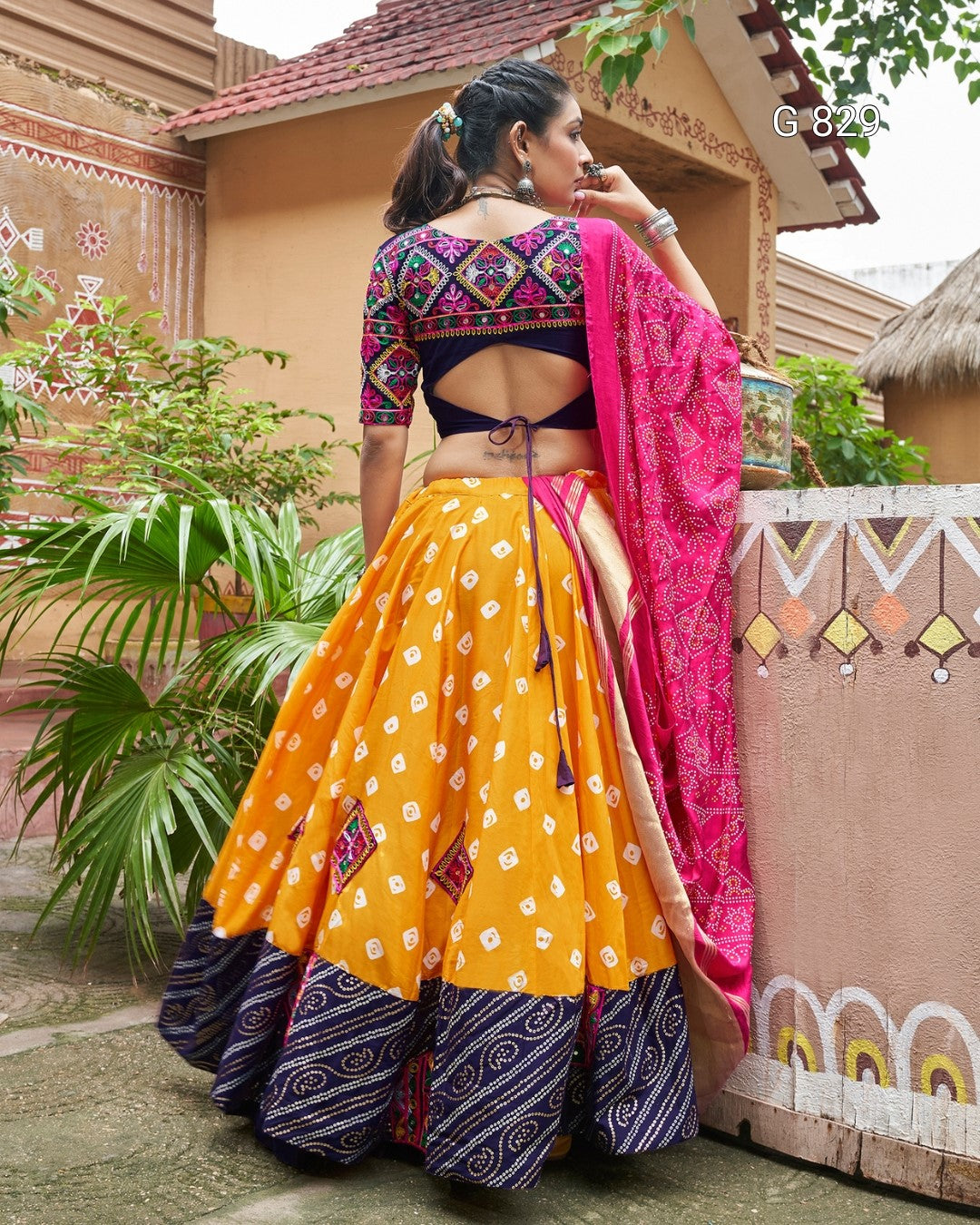 Woman in traditional Indian attire with a colorful saree in front of a decorative wall.