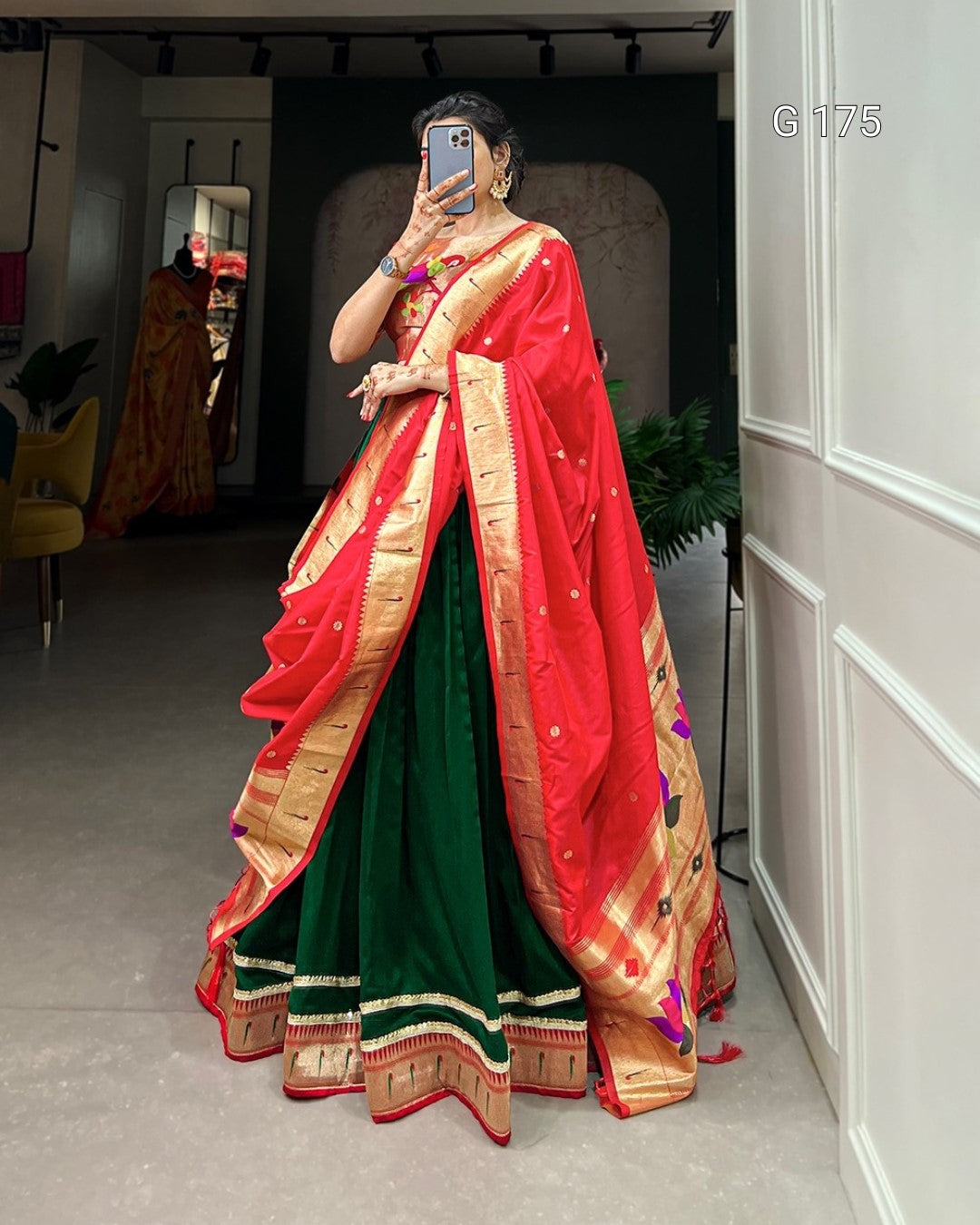 Person wearing a traditional saree with red and green colors in an indoor setting.