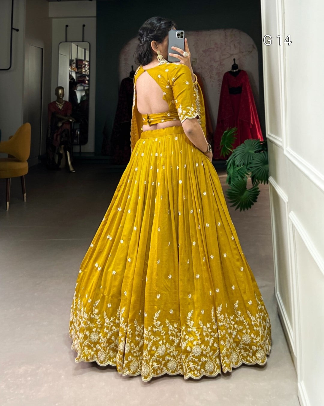 Person wearing a yellow traditional outfit with floral patterns in a room.