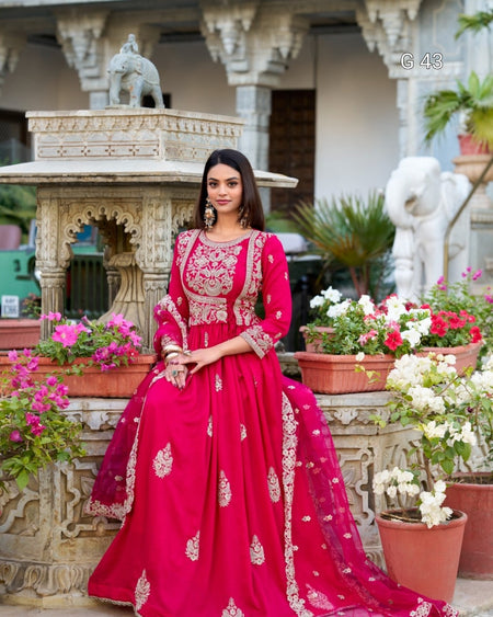 Woman in a red traditional outfit with floral decorations in an outdoor setting.