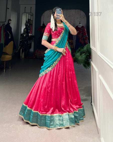 Person wearing a vibrant pink and blue saree in a room with white walls and a chair.