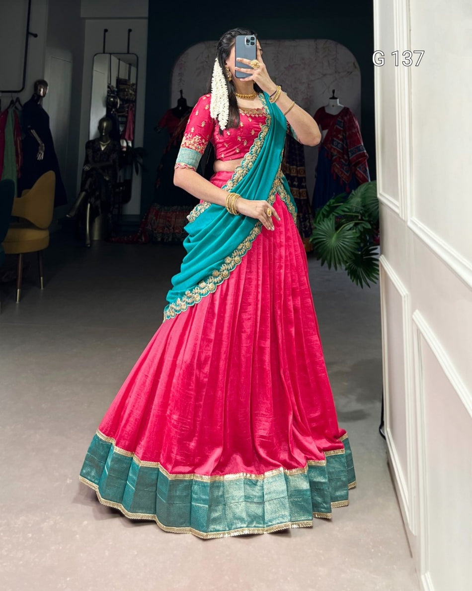 Person wearing a vibrant pink and blue saree in a room with white walls and a chair.