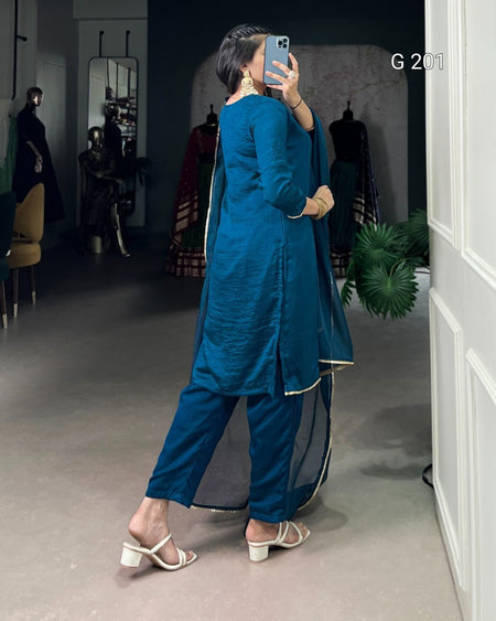 Woman taking a mirror selfie wearing a blue traditional outfit in a store setting.