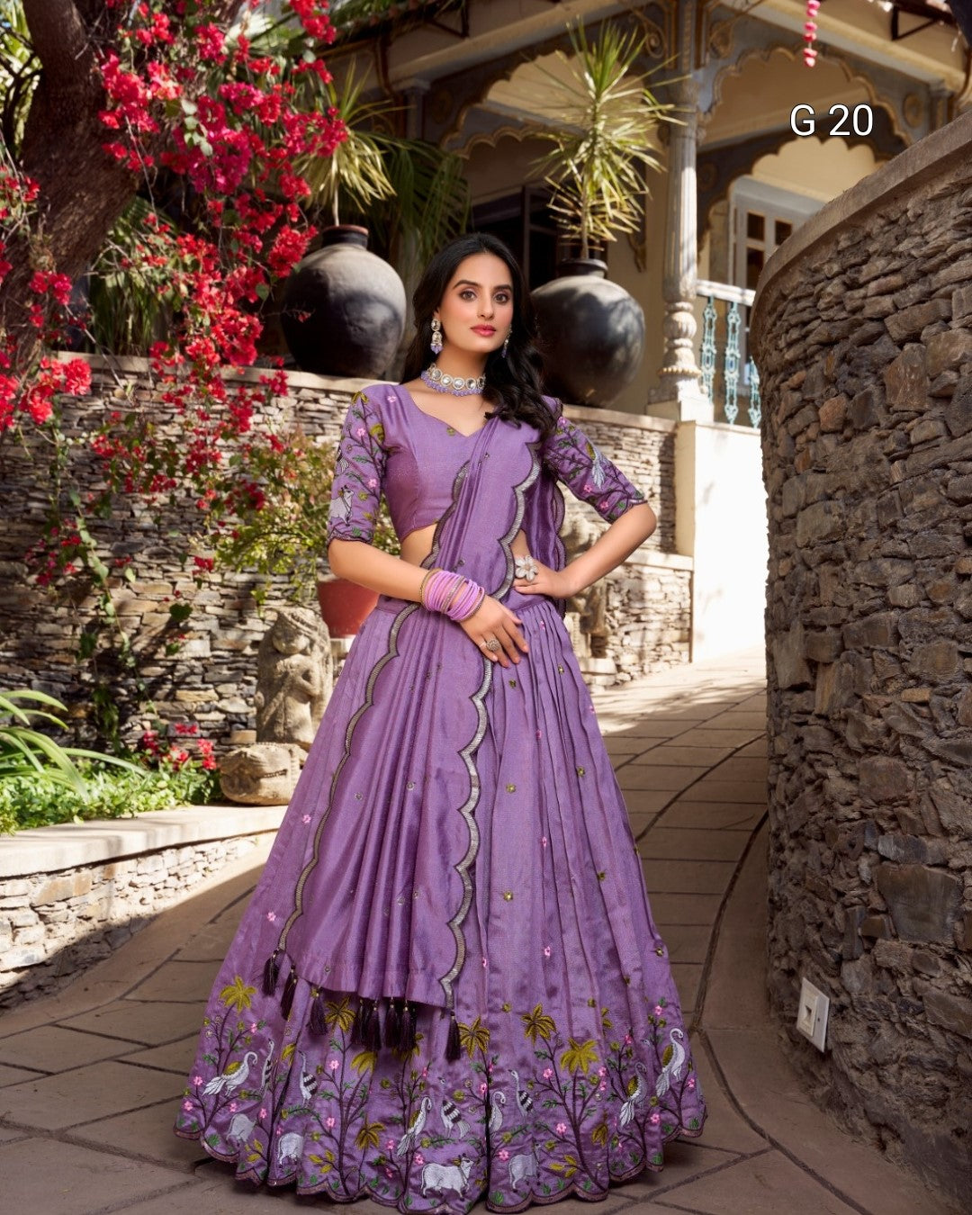 Woman in a purple traditional outfit standing outdoors with decorative elements.