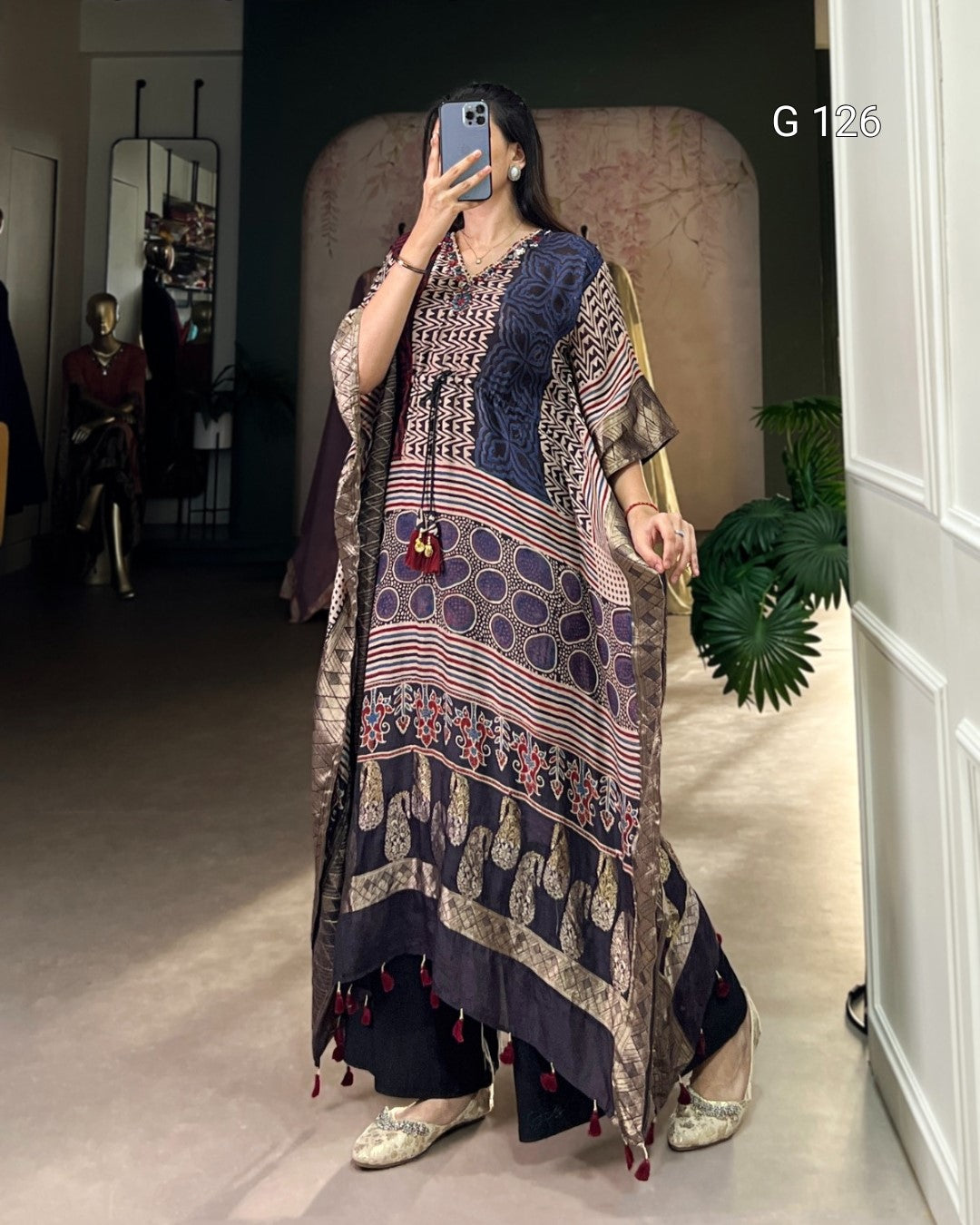 Woman wearing a patterned dress with tassels in an indoor setting