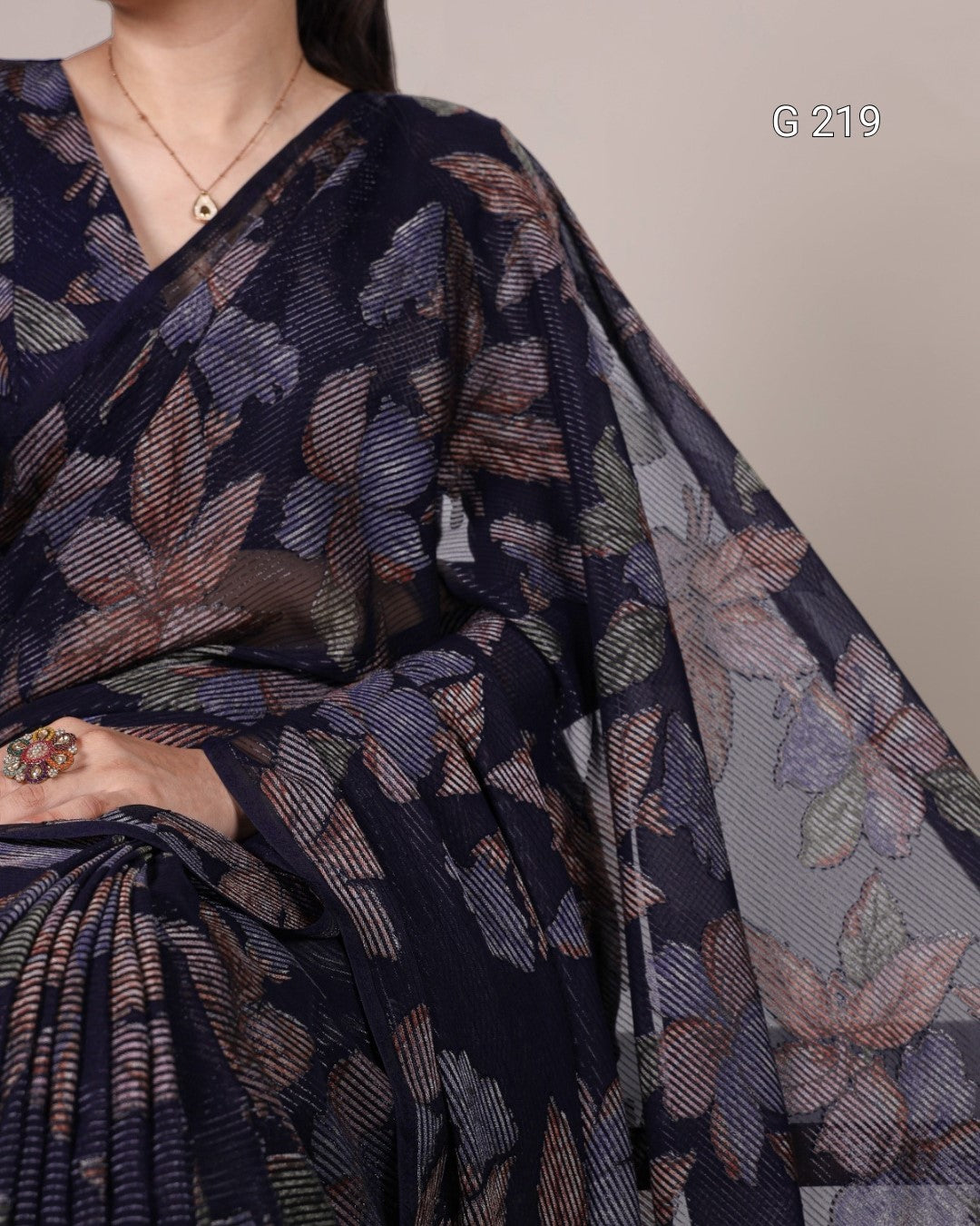 Navy blue saree with floral pattern draped over a person, on a plain background.