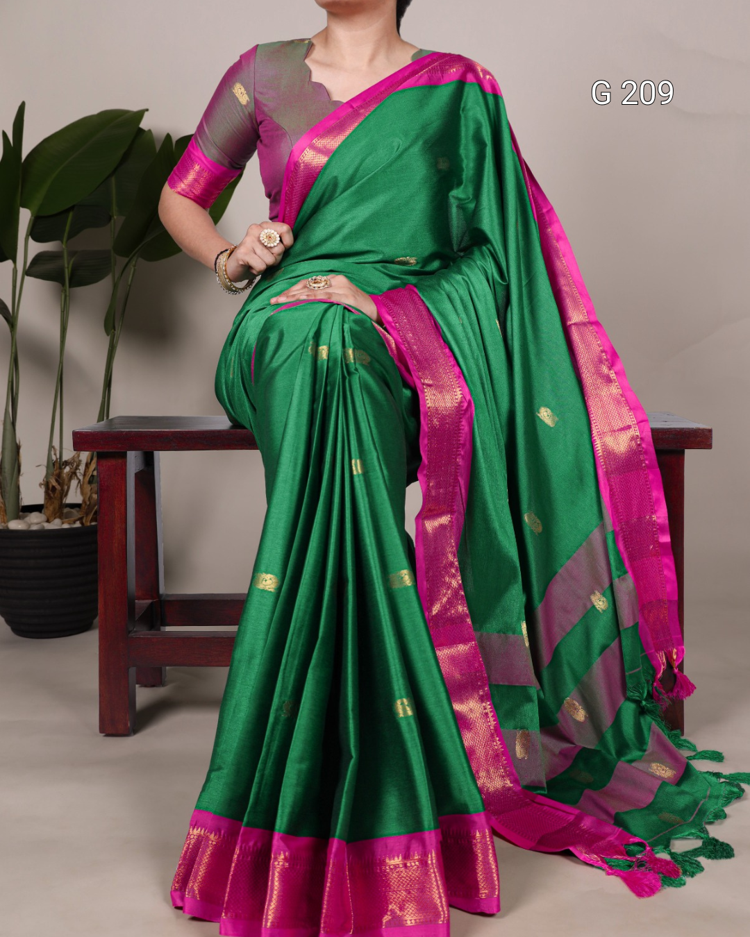 Green and pink saree with gold patterns on a neutral background