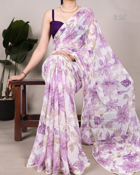 Woman wearing a purple floral saree sitting on a wooden stool.