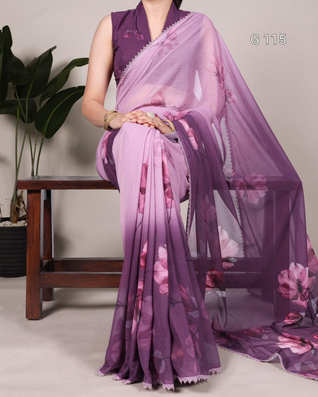 Woman wearing a purple floral saree with a plain background