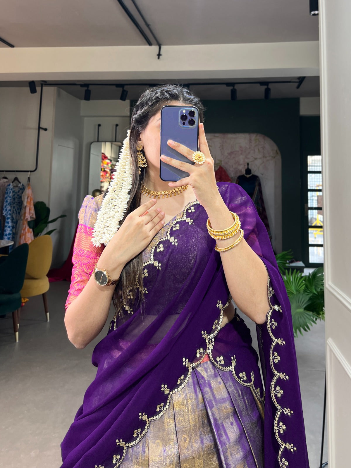Person wearing a purple saree with gold embroidery in an indoor setting.