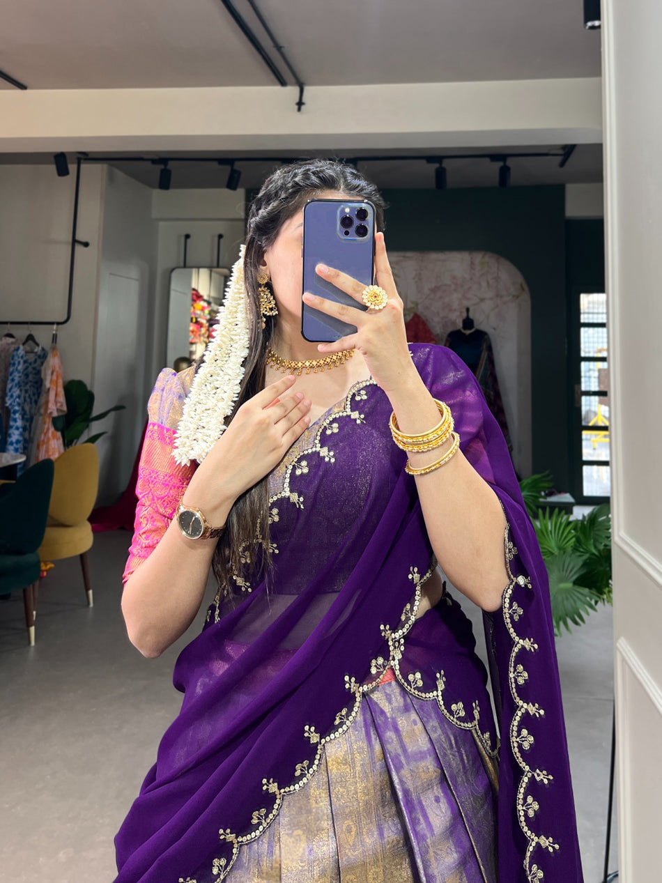 Person wearing a purple saree with gold embroidery in an indoor setting.