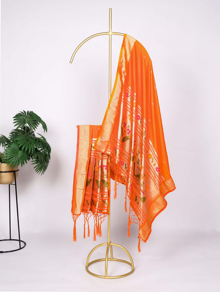 Orange scarf with floral patterns draped over a gold stand against a white background