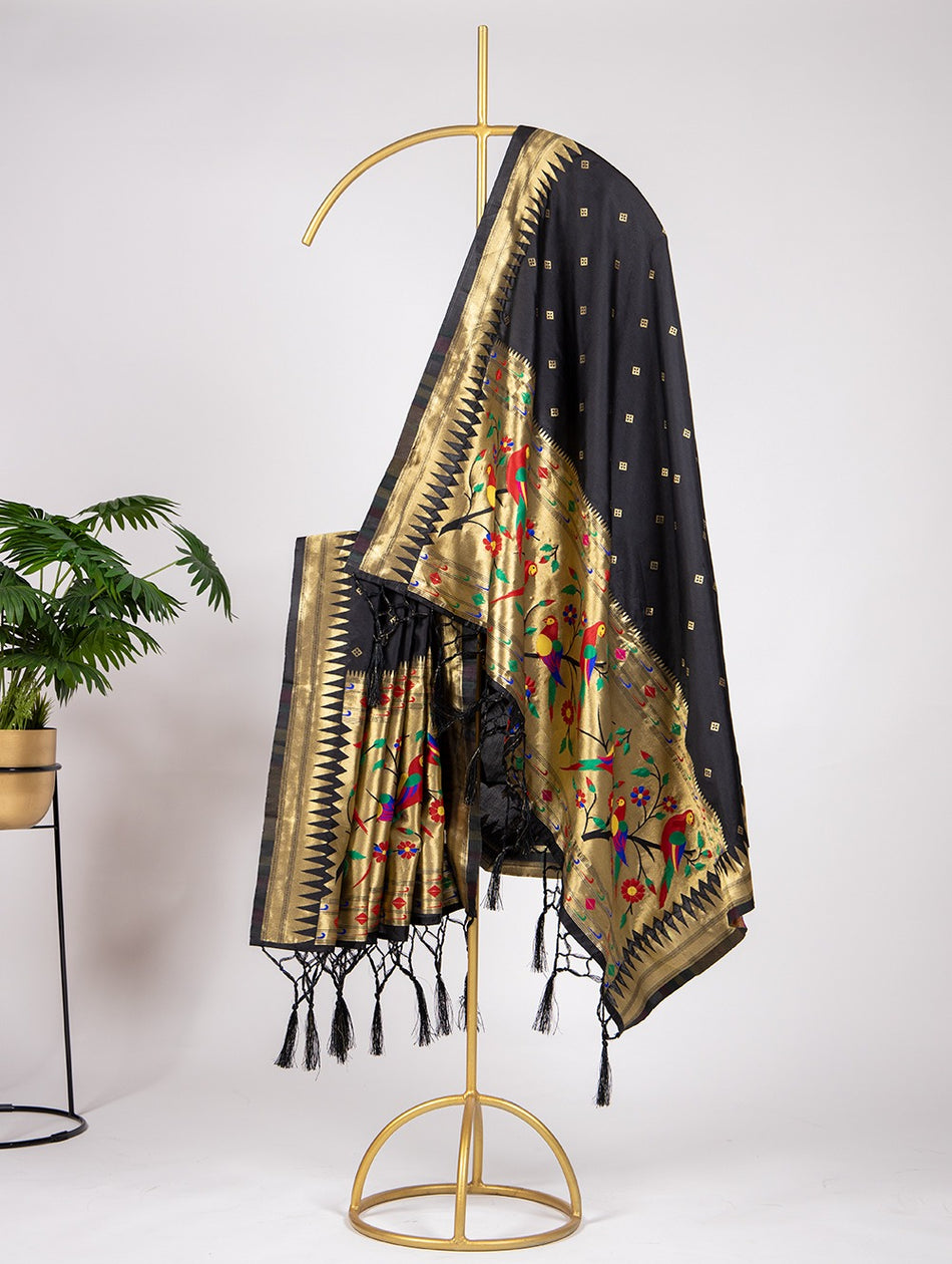 Black and gold embroidered scarf with tassels on a gold stand against a white background