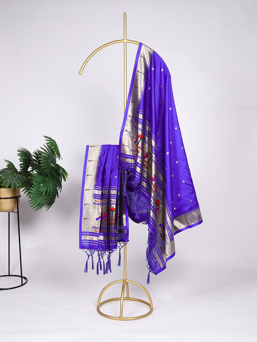 Purple scarf with white patterns draped over a gold stand on a white background
