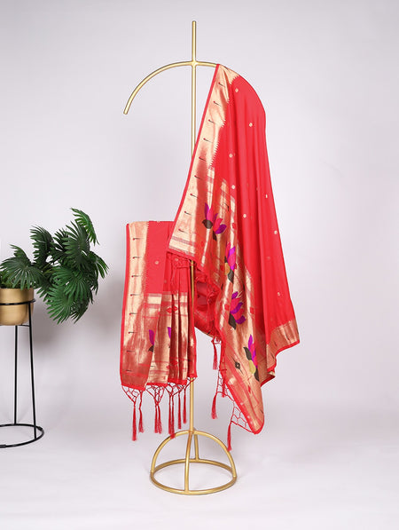 Red saree with floral patterns on a gold stand against a white background