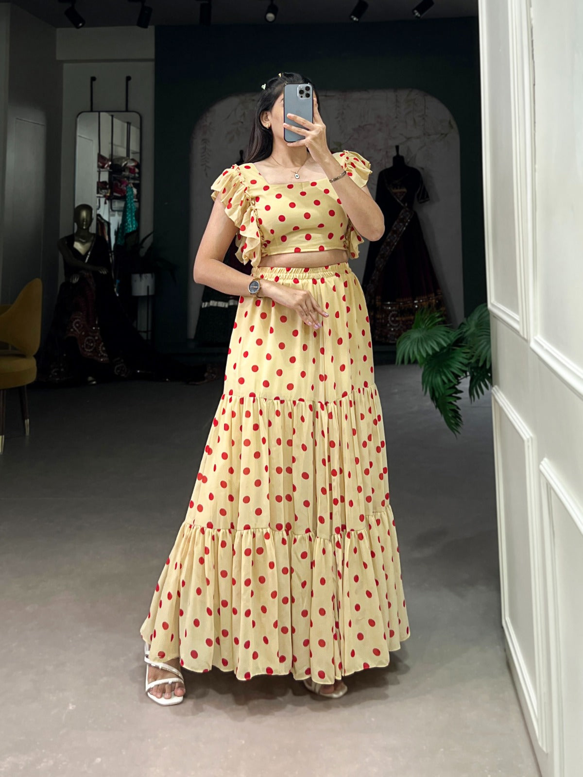 Woman wearing a yellow dress with red polka dots taking a mirror selfie.