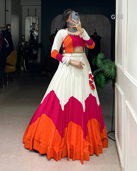Woman taking a mirror selfie wearing a colorful traditional outfit with an orange, white, and pink design.