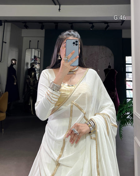 Woman wearing a white saree with gold accents in a store setting.