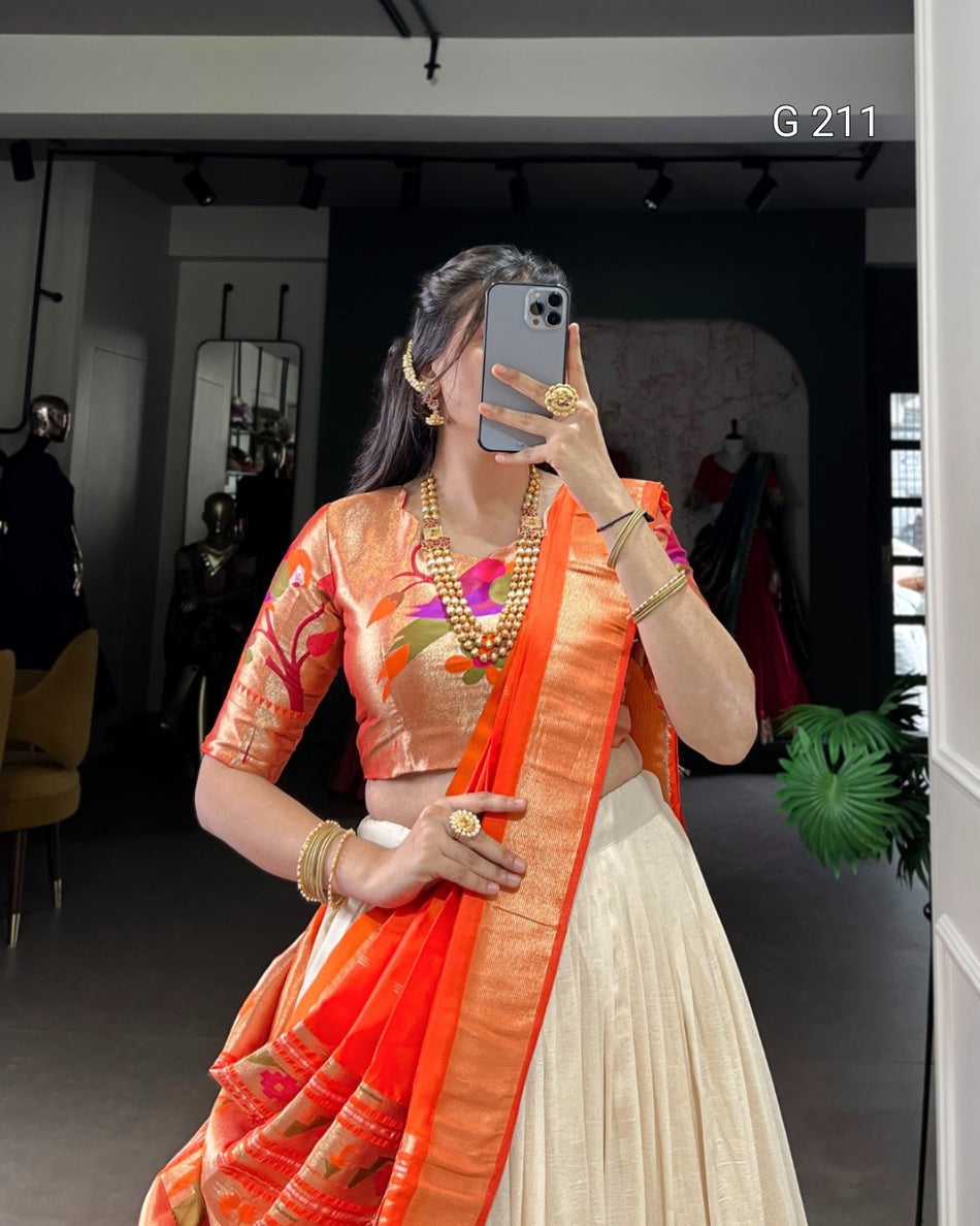 Woman in traditional orange and white saree taking a mirror selfie.